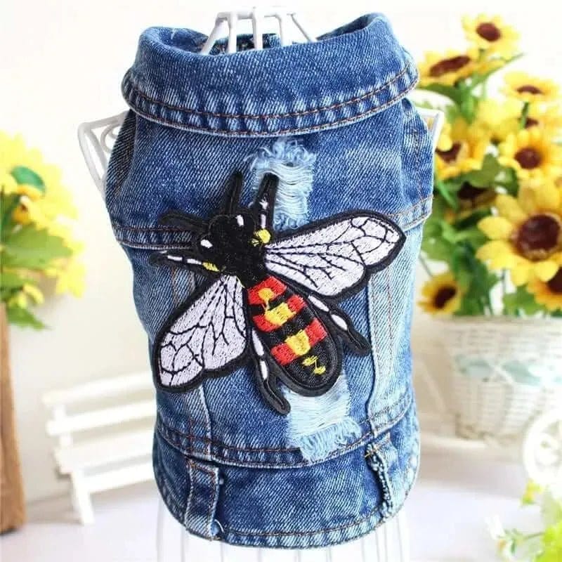 Blue denim dog jacket with a large embroidered bee patch on the back, displayed on a white wire mannequin.