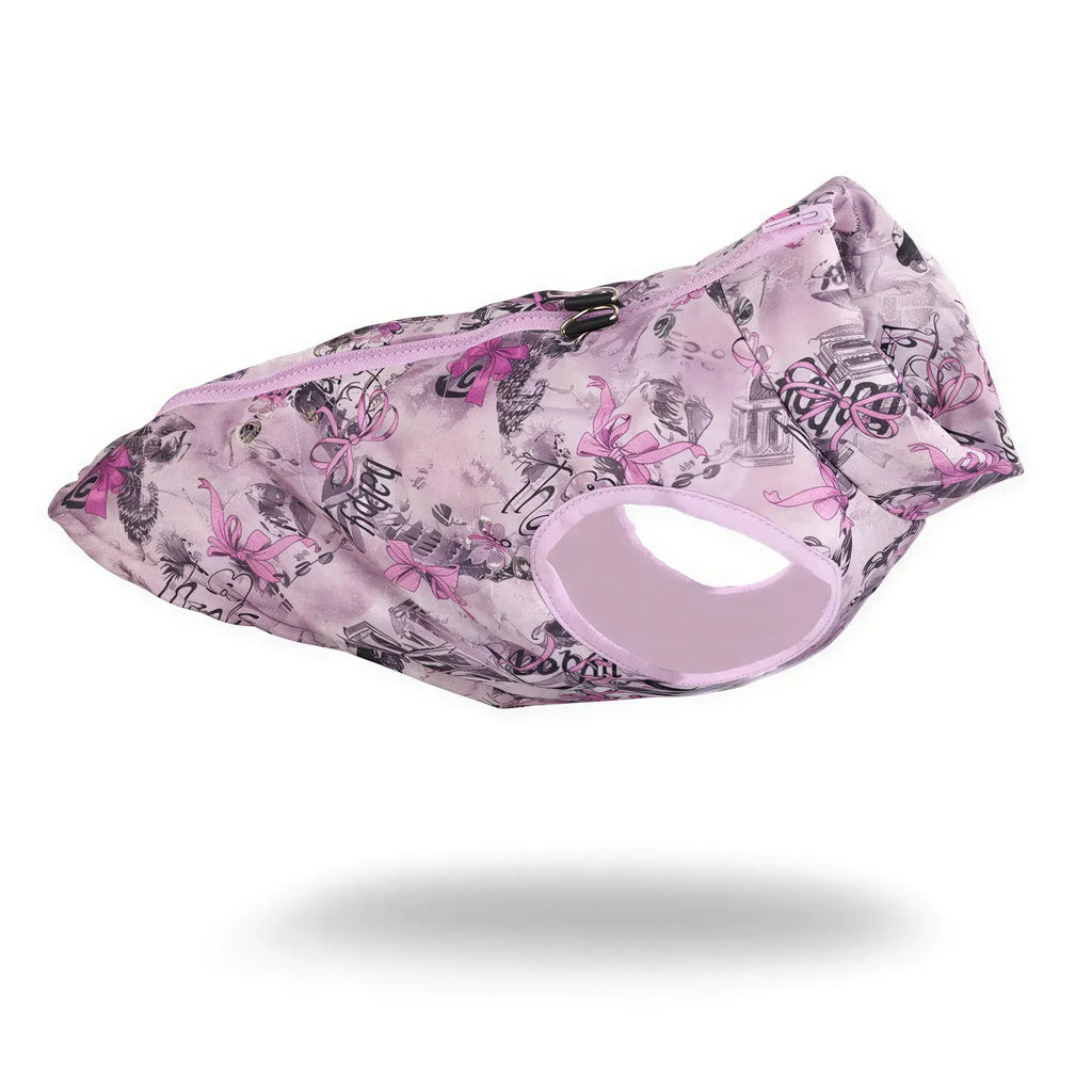 Pink quilted fabric dog puffer jacket with a purple zipper and a print featuring bows, buildings, and the word happy.