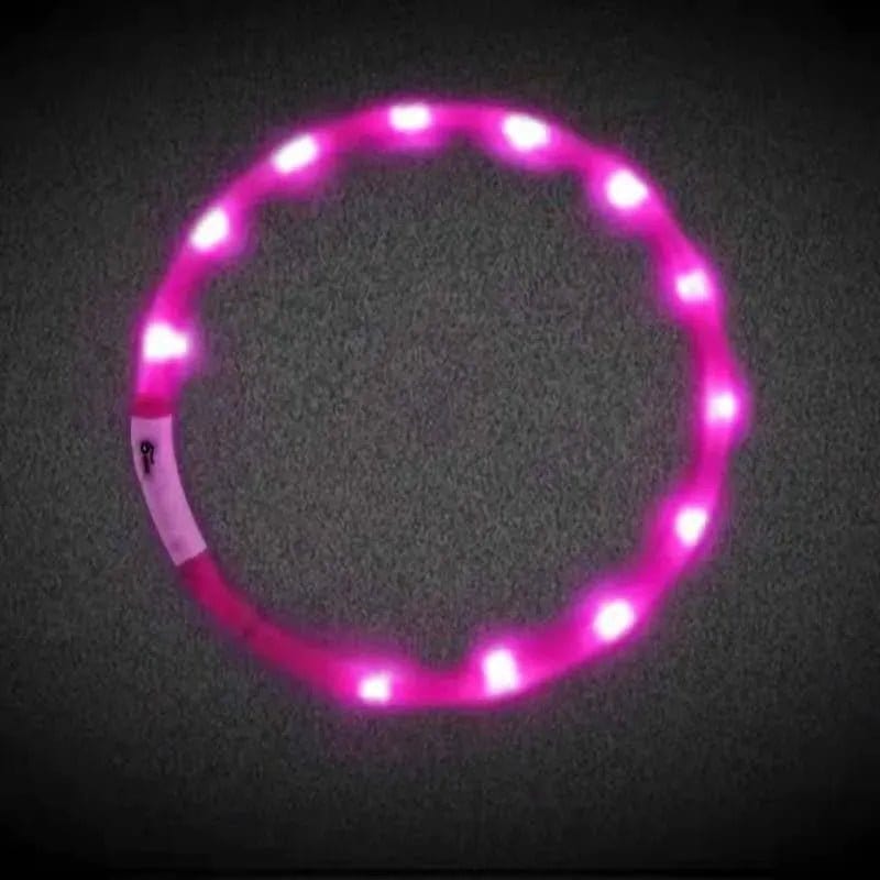 One circular pink plastic LED dog collar glowing with multiple bright lights against a dark background.