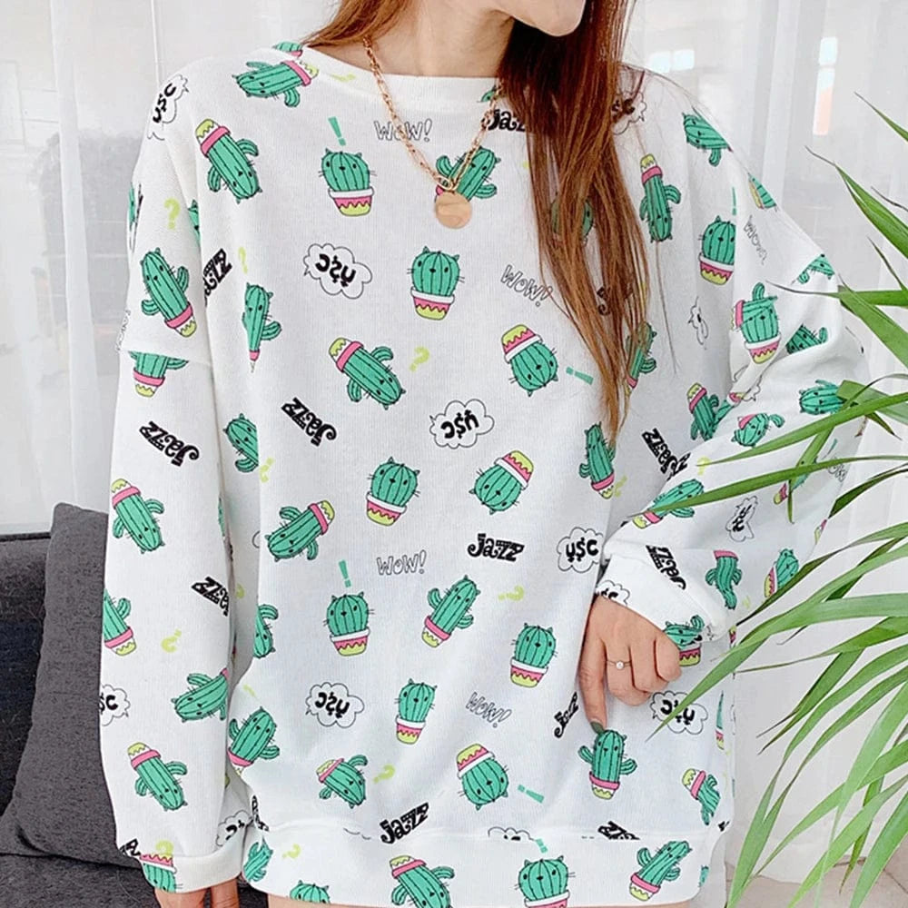 A person wearing a long-sleeved pajama top with a cactus pattern, matching a potential pet pajama set, sitting on a couch.